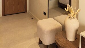 A modern hotel room with a wooden door, a round wooden table, a beige upholstered bench, and a large mirror reflecting the room. - Pyramids Pavilion Boutique Hotel (Giza)