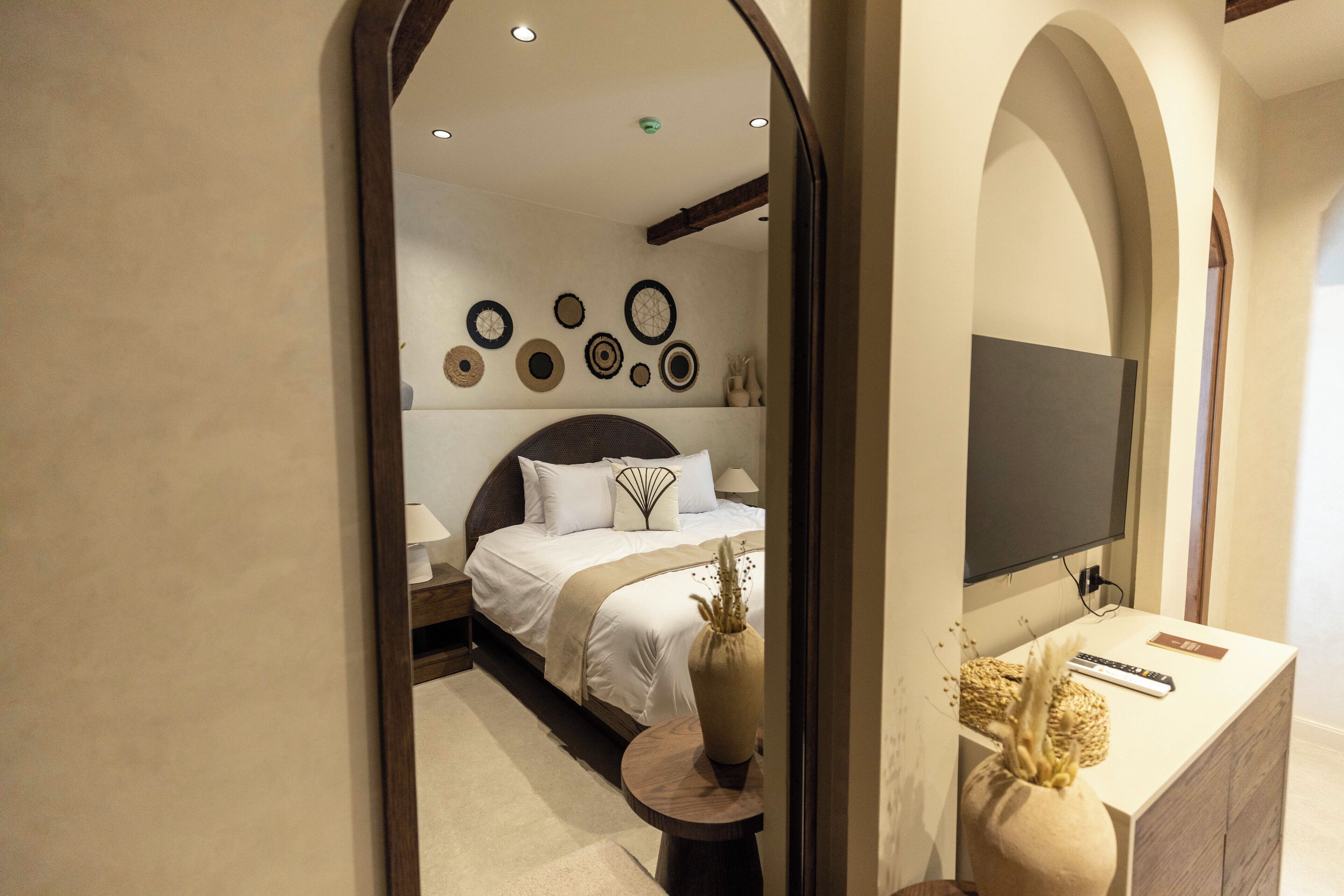 Une chambre à coucher avec un lit, une table de chevet et un miroir qui reflète la pièce.
