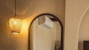 A bedroom with a large mirror, a bedside table with a vase, a hanging light fixture, and a bed with a white comforter. - Pyramids Pavilion Boutique Hotel (Giza)