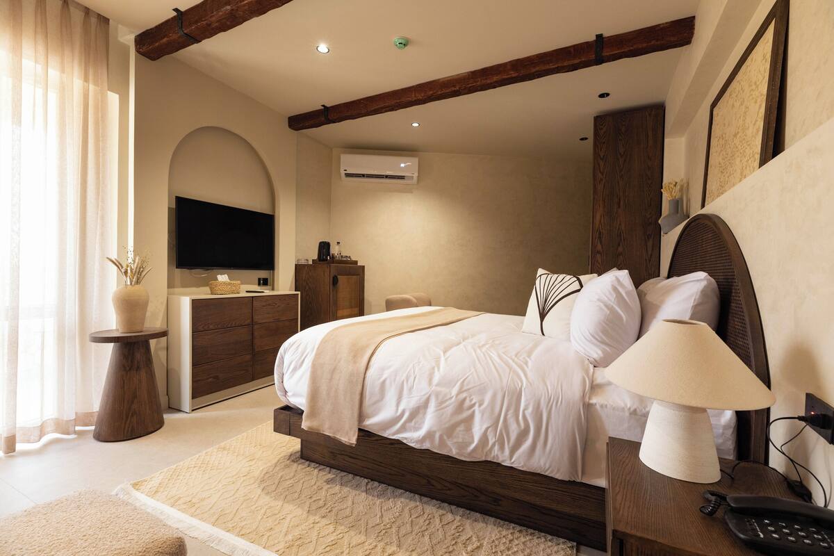 A modern bedroom with a large bed, bedside table, and a TV mounted on the wall.