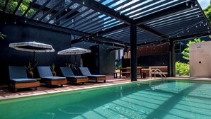 A pool area with lounge chairs and umbrellas, surrounded by a covered structure with a metal roof. - Villa Cruz, Private Pool, Near Beach, Concierge (Tulum)