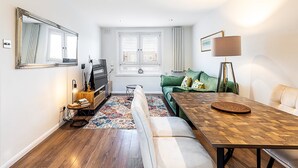 Un espacio habitable compacto con un sofá, una mesa de centro, un televisor y una lámpara.