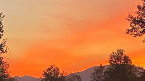 A sunset with a golf cart and trailer in a rural setting.