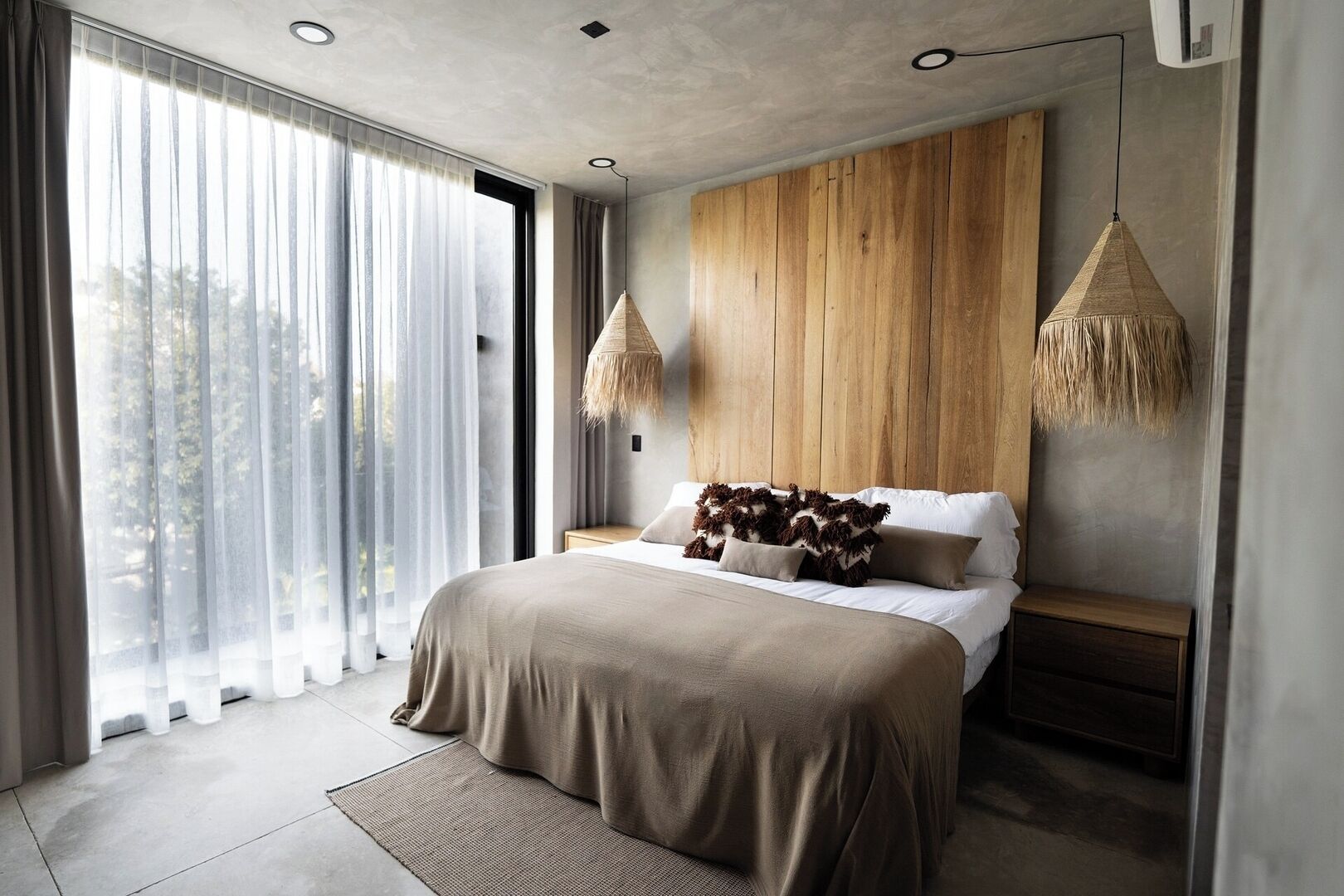 Un dormitorio moderno con una cama grande, cabecero de madera y dos lámparas colgantes.