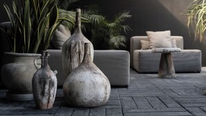 A modern outdoor seating area with a grey sofa, a small table, and two rustic vases. - Design Luxury Villa, 3 Pools, Rooftop, Near Beach (Tulum)