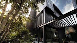 Een modern huis met een glazen gevel, terras en tuin.