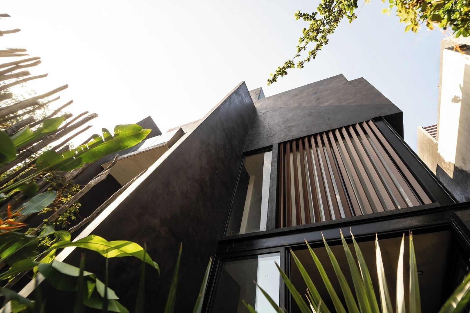 A modern building with a sloped roof, large windows, and a view of surrounding greenery.