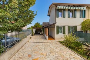 A two-story house with a stone-paved courtyard, green shutters, and a fenced area with potted plants. - FERRY OLD HOUSE (TREPORTI)