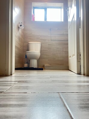 A bathroom with a toilet, a small window, and a tiled floor. - Lindiwe House Self-Catering (Victoria Falls, Zimbabwe)
