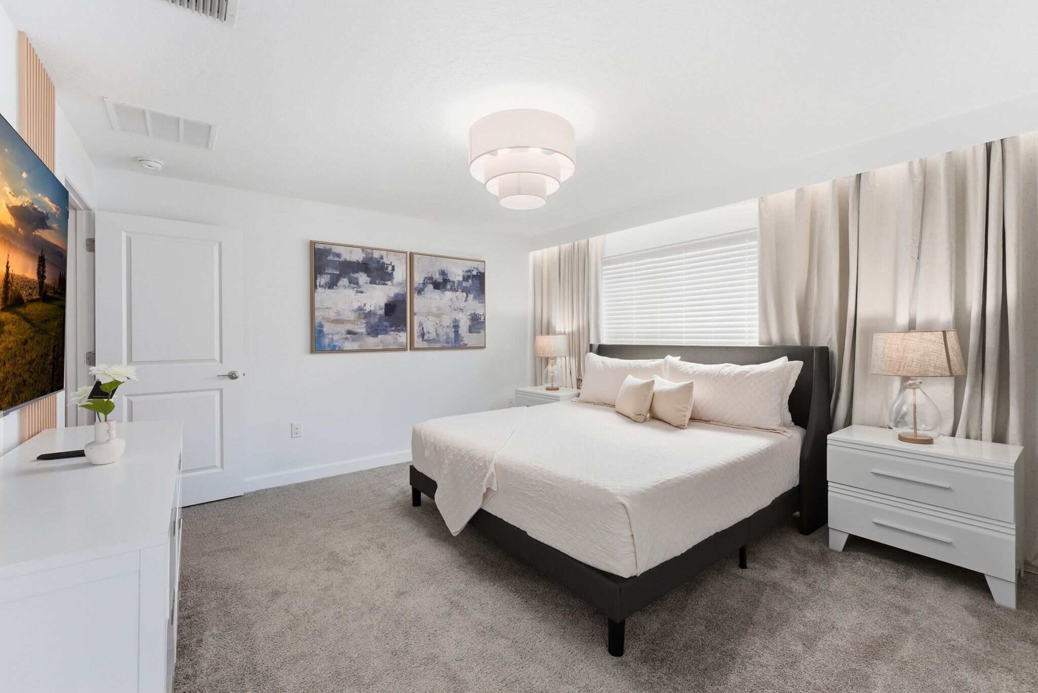 A bedroom with a bed, nightstands, a lamp, a painting, and a window with curtains.