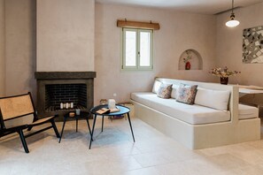 Een woonkamer met een open haard, een bank, een salontafel en een fauteuil.