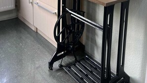 A kitchen with a wooden table, two wine glasses, and a black metal stool.