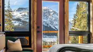Un dormitorio con una cama, un sillón verde y una ventana con vistas a la montaña.
