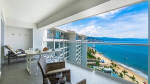 A balcony with a view of a beach and ocean. - Stylish Beachfront 2BR | Balcony Sunsets & Pools (Puerto Vallarta)