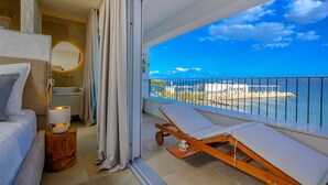A balcony with a view of the sea, a wooden lounge chair, a small table with a candle, and a bed with a nightstand. - Beachfront Villa Lara with Pool (Duće)