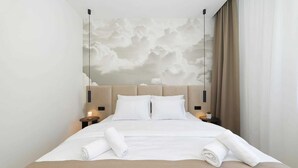 A hotel room with a large bed, a headboard with a cloud mural, two bedside tables with lamps, and a window with curtains. - Luxury Villa Pasman Emerald with Pool (Tkon)