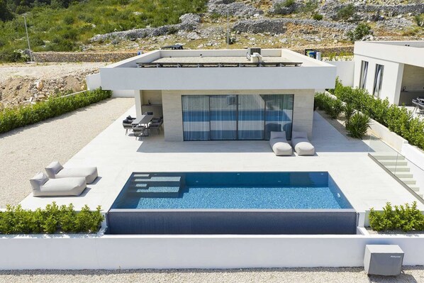 Une maison moderne dotée d’une piscine, d’un espace extérieur aménagé et offrant une vue sur le paysage environnant.