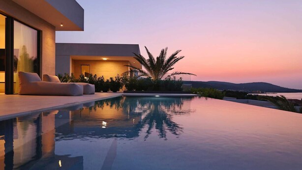 Una piscina a sfioro moderna con vista sul tramonto e sulle montagne.