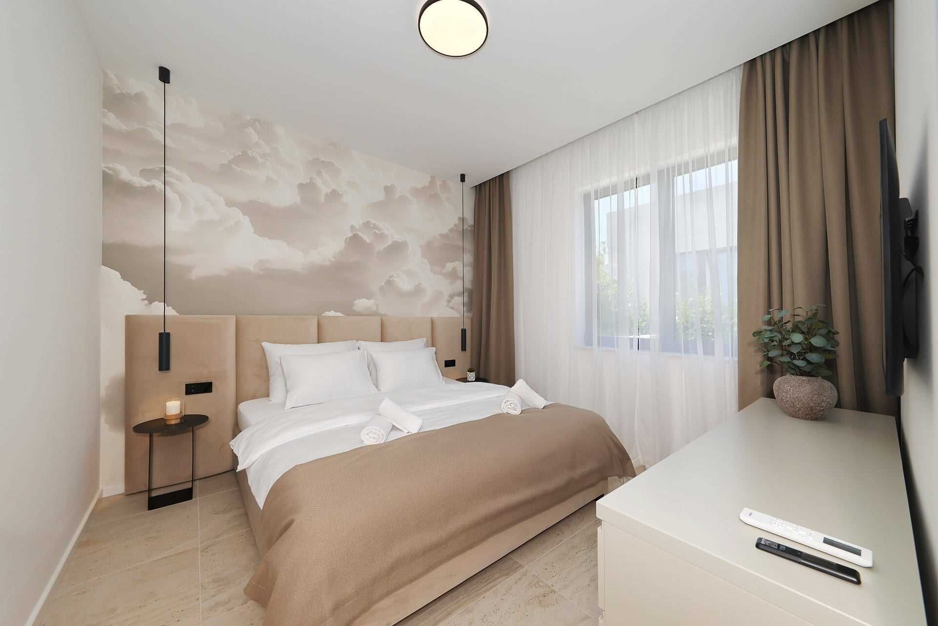 A modern hotel room with a large bed, a bedside table, a TV, and a window with curtains.