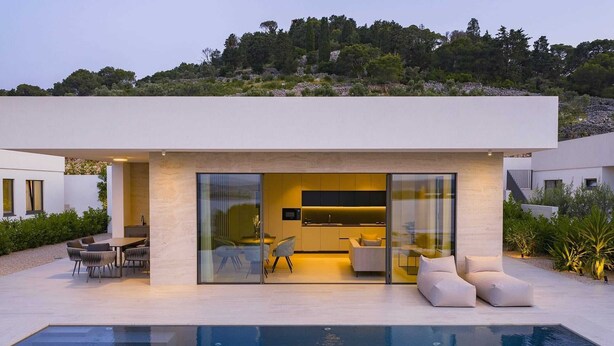 A modern house with a swimming pool, a dining area, and a kitchen visible through large glass doors. - Luxury Villa Pasman Turquose with Pool (Tkon)