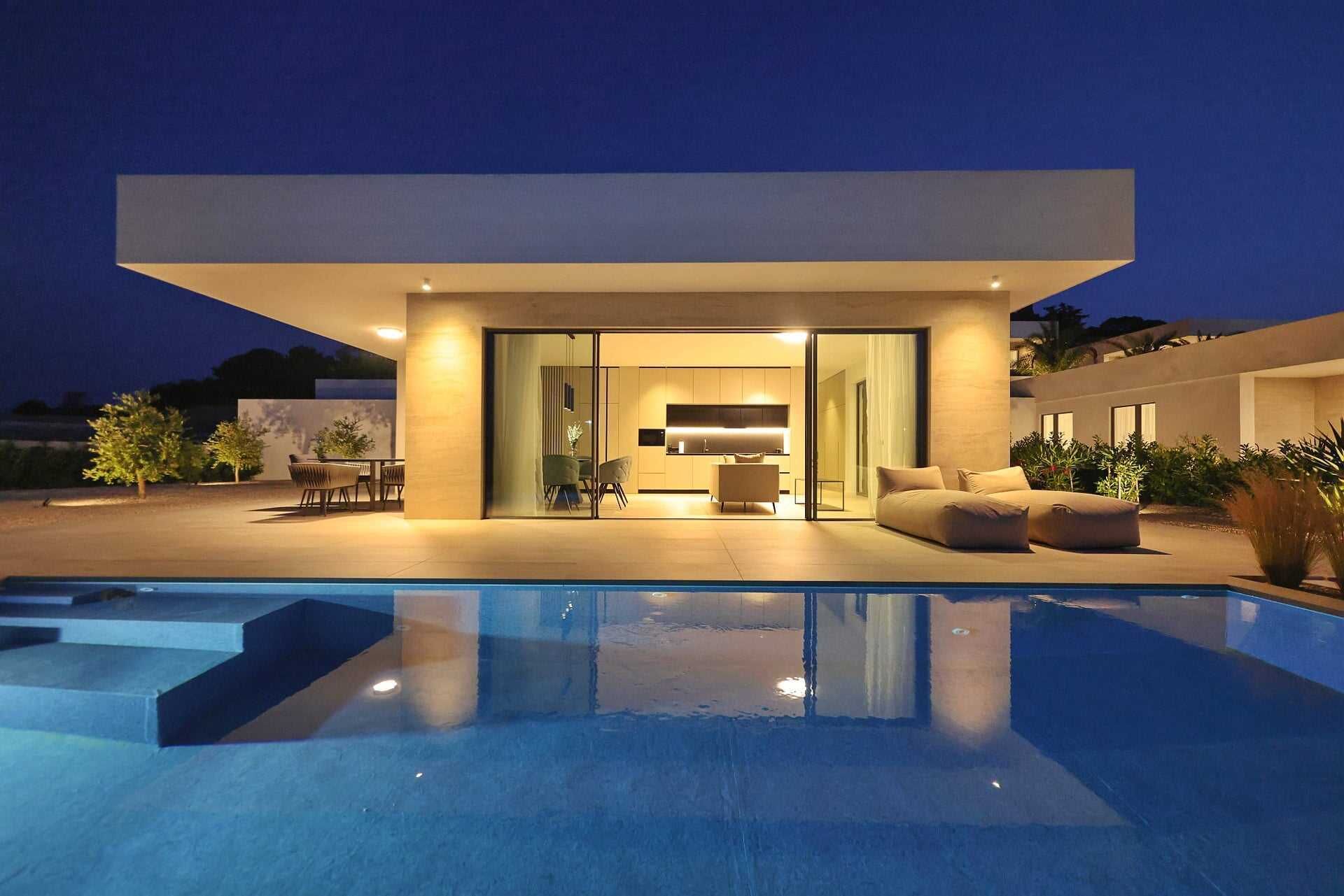 Een modern huis met een zwembad, een eethoek en een woonkamer met een bank en een televisie.