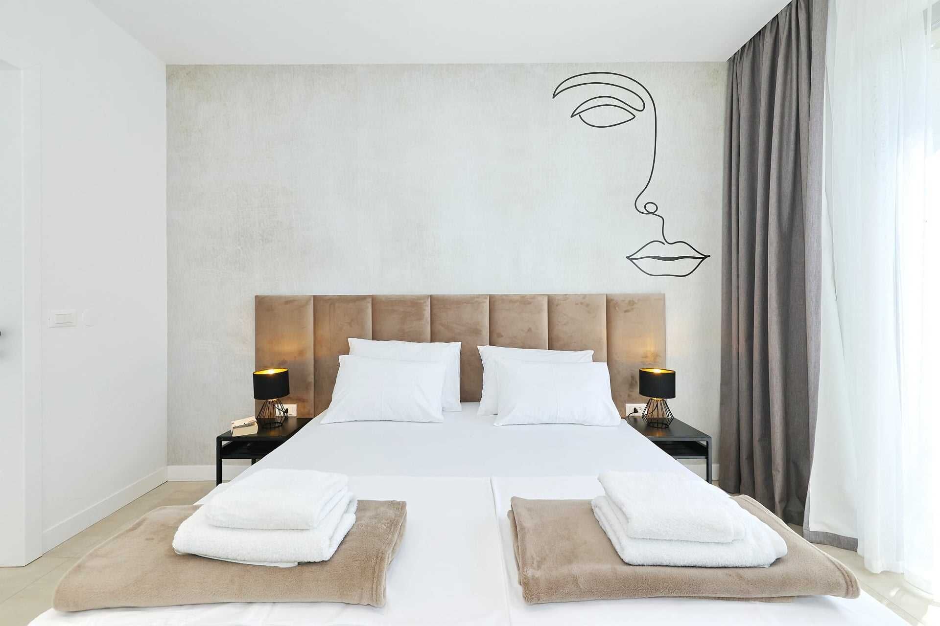 A modern hotel room with a large bed, two bedside tables, and a wall art piece.