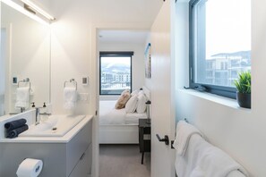 A modern hotel bathroom with a large mirror, a sink with a towel, and a window with a city view. - Avalanche Ridge (Revelstoke)