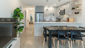A modern kitchen with a central island, built-in appliances, and a dining area with black chairs. - Avalanche Ridge (Revelstoke)