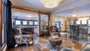 A spacious living room with a large mirror, leather armchairs, and a chandelier. - Walk to Park City Mountain Ski Resort & Main St The House in Woodside Ave by Avantstay (Park City)