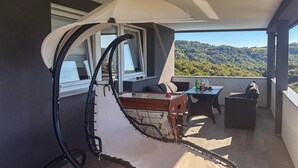 Ein Balkon mit Esstisch, einer Couch und einem Baldachin.
