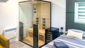 Ein Schlafzimmer mit einem gläsernen Stauraum, einem Bett mit gestreifter Bettwäsche und einem Fenster mit Jalousien.