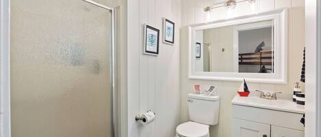 A bathroom with a toilet, sink, mirror, and framed artwork on the wall.