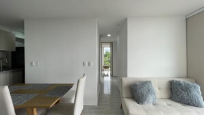 A modern living room with a sofa and a dining table. - Apartment 3 Bedrooms - Swimming Pool - City View (Armenia)