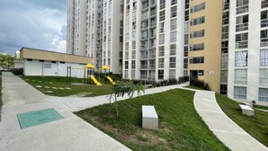 A modern apartment building with a playground, green lawns, and a clear sky. - Apartment 3 Bedrooms - Swimming Pool - City View (Armenia)