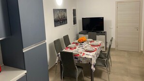 A dining area with a table set for four, a television on a stand, and a door in the background. - Detached house with private parking 250 meters from the spa train station (Montegrotto Terme)