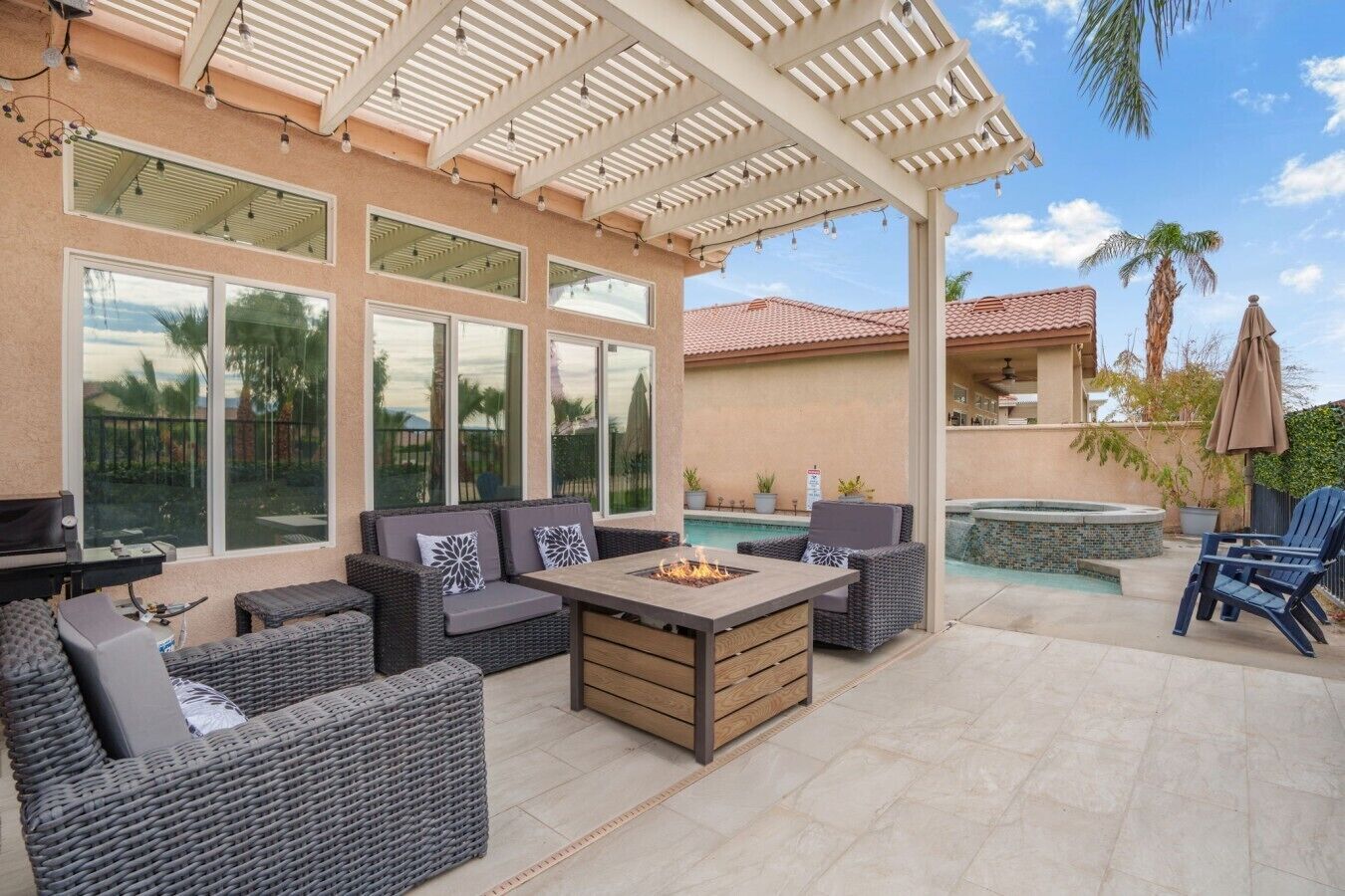 Eine Terrasse im Freien mit Korbmöbeln, einer Feuerstelle und einem Poolbereich.