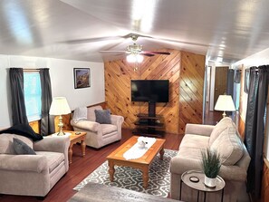 Ein Wohnzimmer mit zwei Sofas, einem Couchtisch, einem Fernseher und einem Deckenventilator.