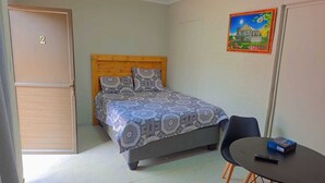 Een slaapkamer met een bed, een stoel, een tafel en een schilderij aan de muur.