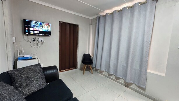 Een woonkamer met een televisie, een bank, een stoel en een deur.