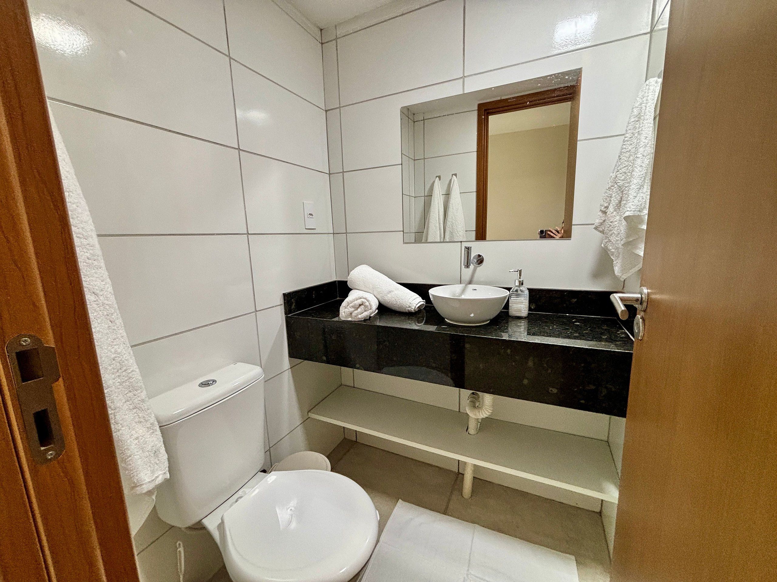 Un baño con inodoro, lavabo, espejo y barra para toallas.