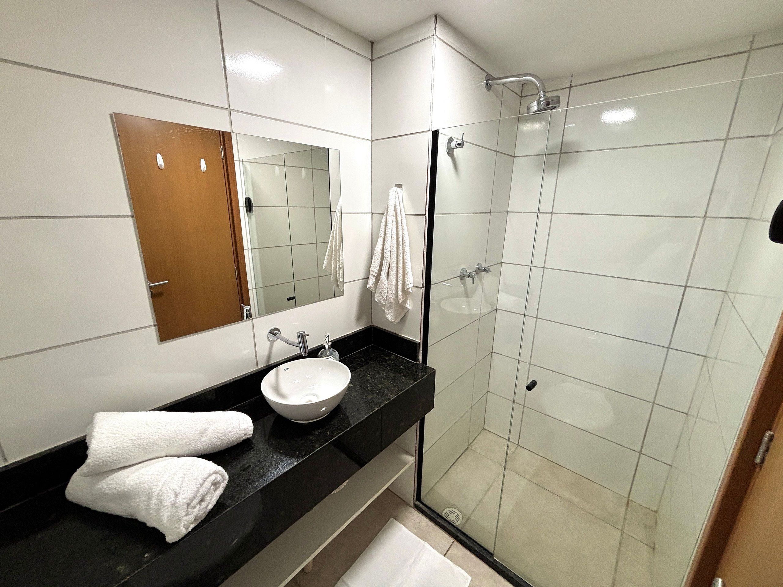 Une salle de bain moderne avec une douche à parois de verre, un lavabo blanc et un miroir au-dessus du lavabo.
