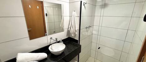 Une salle de bain moderne avec une douche à parois de verre, un lavabo blanc et un miroir au-dessus du lavabo.