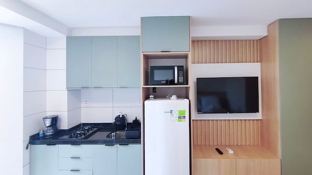 A compact kitchen with a microwave, stove, and refrigerator. - Max Carneiros Suites - Com e sem Piscina Privativa (Tamandaré)