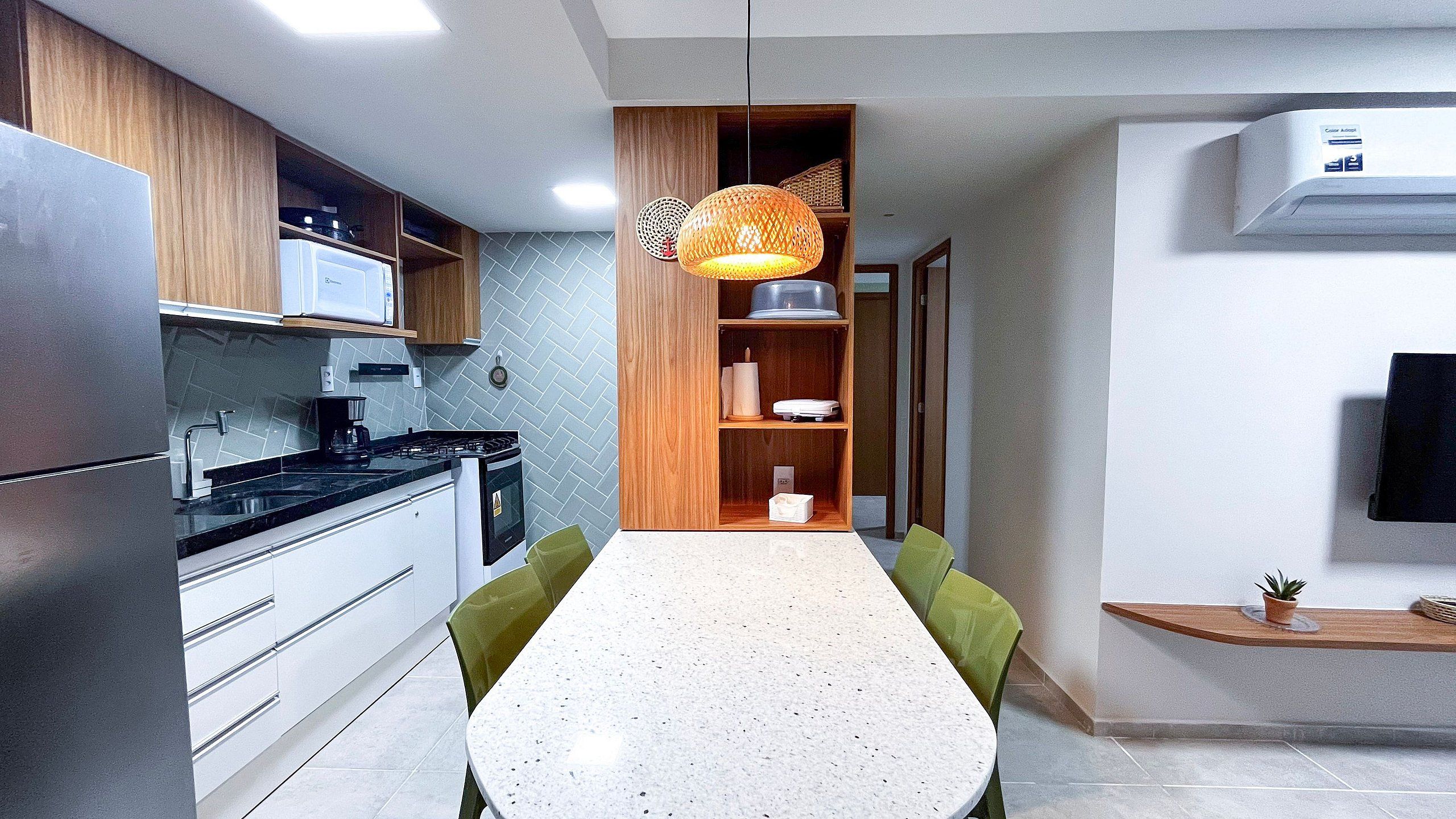 Une cuisine moderne avec un coin repas, comprenant une cuisinière, un four à micro-ondes et un luminaire suspendu.