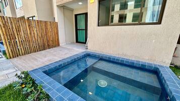 Piscina com azulejos azuis, cerca de madeira e um edifício com uma janela.