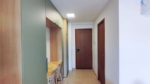 A hallway with a wooden door, a bench, and a wall-mounted shelf. - Max Carneiros Suites - Com e sem Piscina Privativa (Tamandaré)