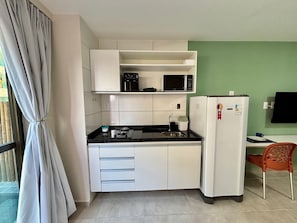 Una cocina compacta con gabinetes blancos, microondas, estufa a gas y refrigerador.