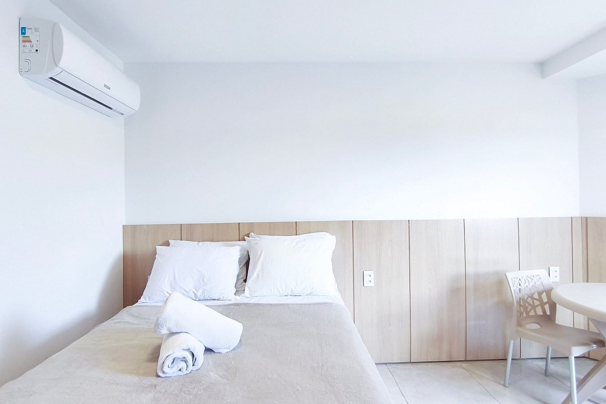 Una habitación de hotel con una cama, una mesa y un equipo de aire acondicionado.