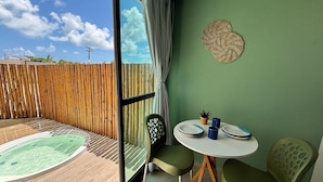A room with a view of the sky, a wooden fence, a hot tub, a table with plates, and two chairs. - Max Carneiros Suites - Com e sem Piscina Privativa (Tamandaré)