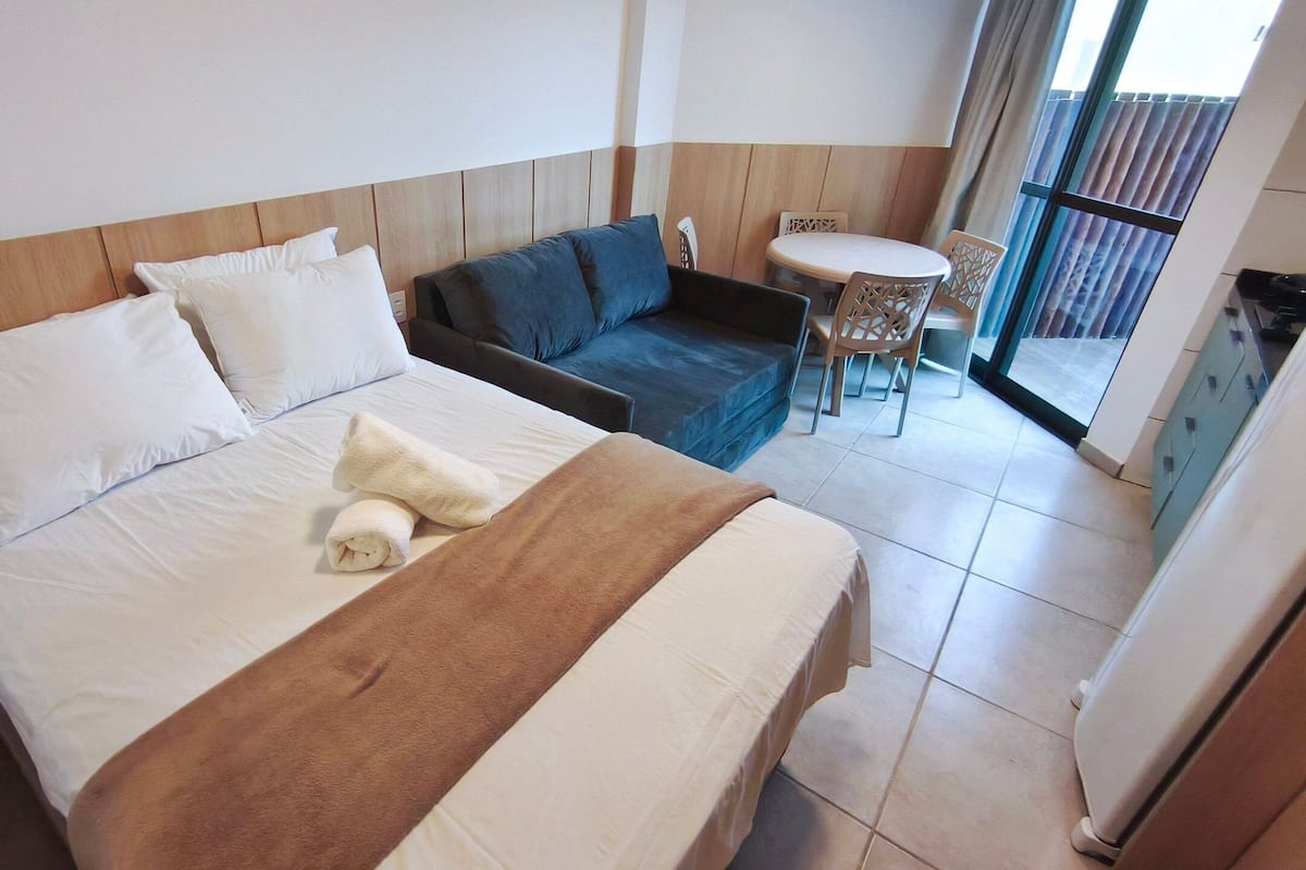 Una habitación de hotel con cama, sofá, una mesita y un balcón con vistas.